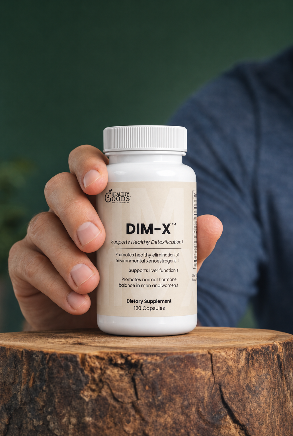 Hand holding a bottle of DIM-X dietary supplement on a wooden surface with a blurred background