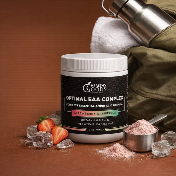 Container of 'Healthy Goods' EAA Complex with strawberries, ice cubes, and a measuring spoon on a brown background